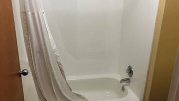 A bathroom with a bathtub, a shower curtain, and a door.