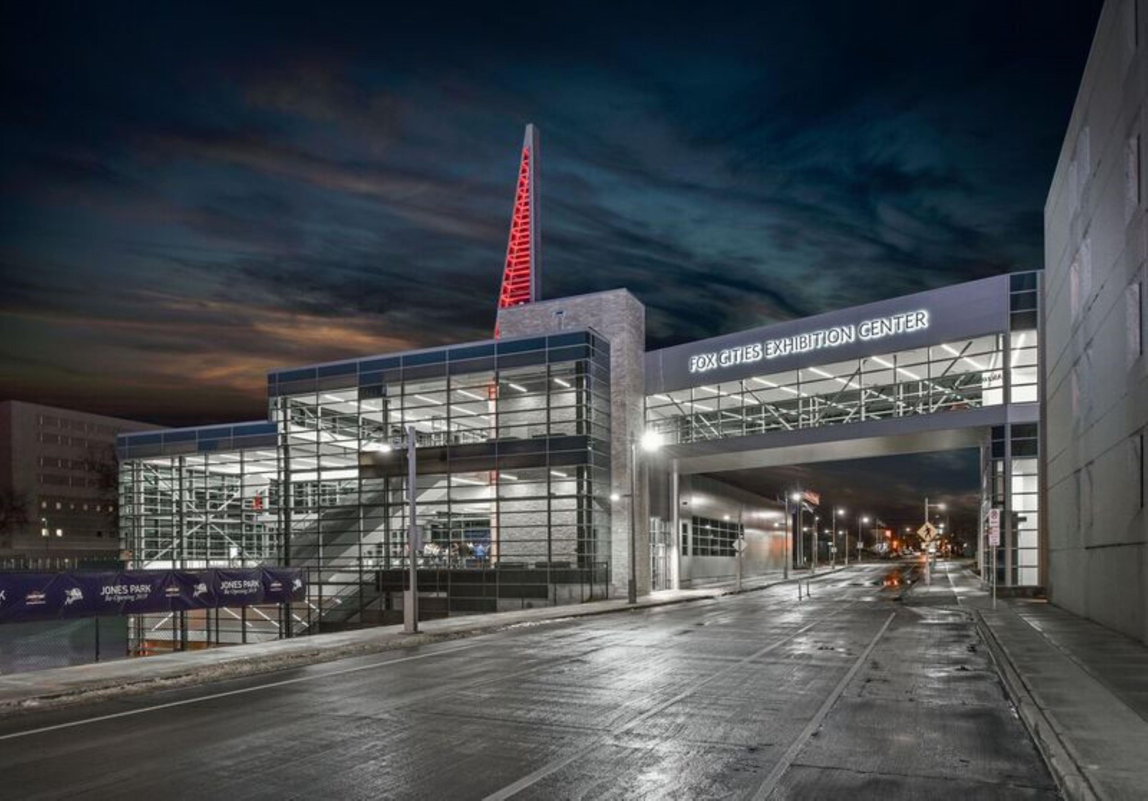A modern building with a glass facade and a prominent red spire, labeled as 'FOX CITIES EXHIBITION CENTER.'