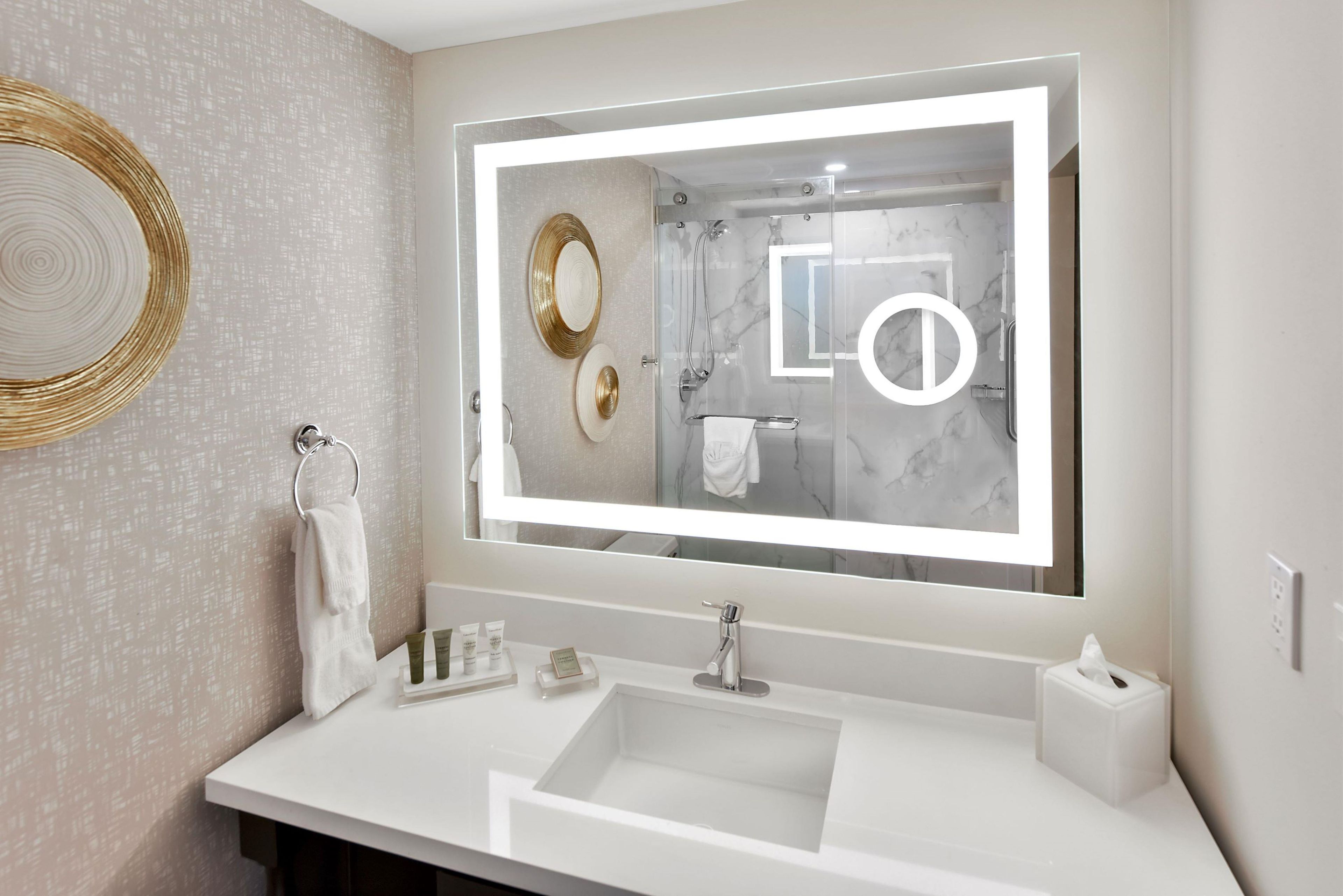A modern bathroom with a large mirror, a sink, and a towel rack.