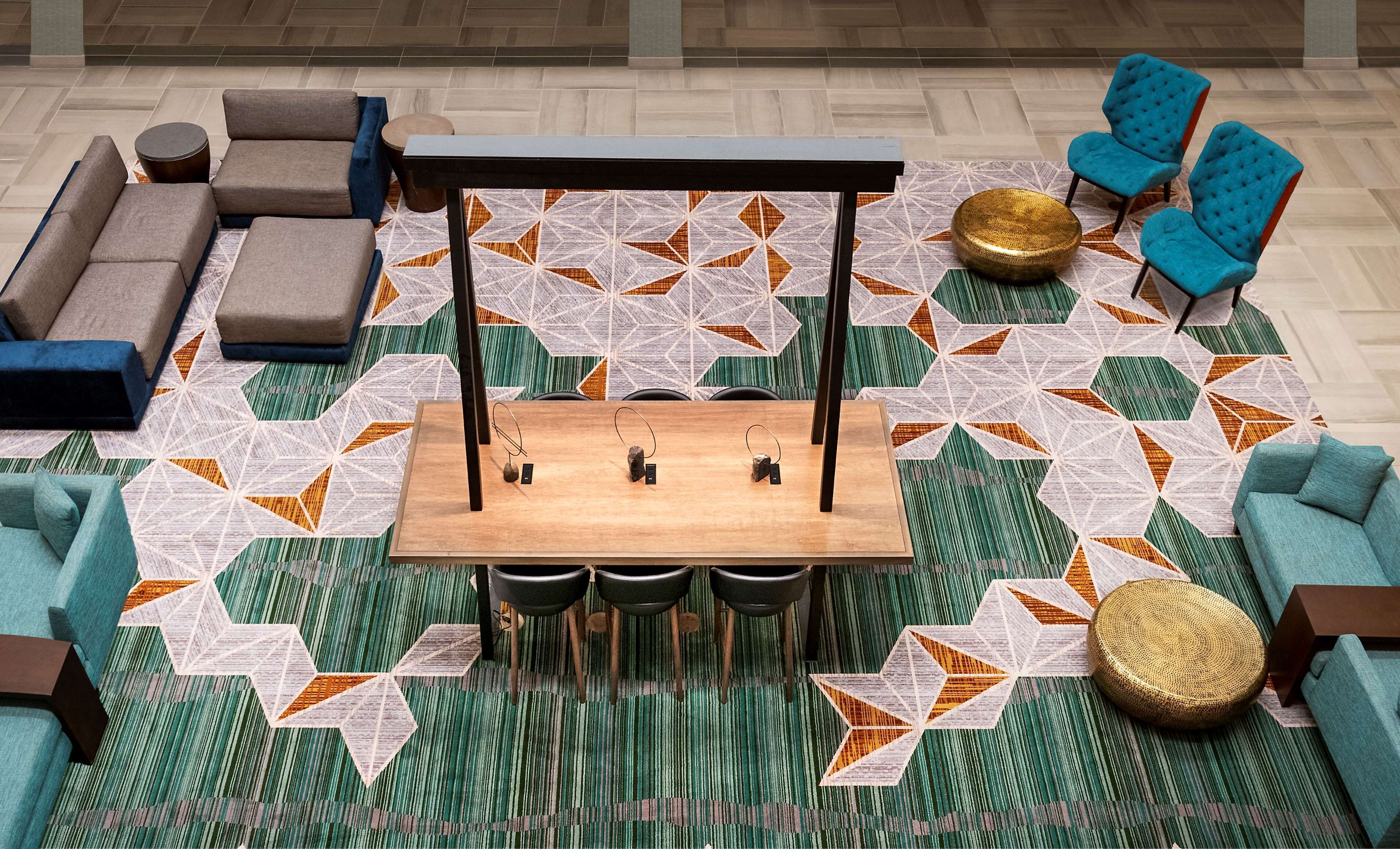 Ein stilvoller Lounge-Bereich mit einem zentralen Holztisch, mehreren Sesseln, Sofas und einem gemusterten Teppich.