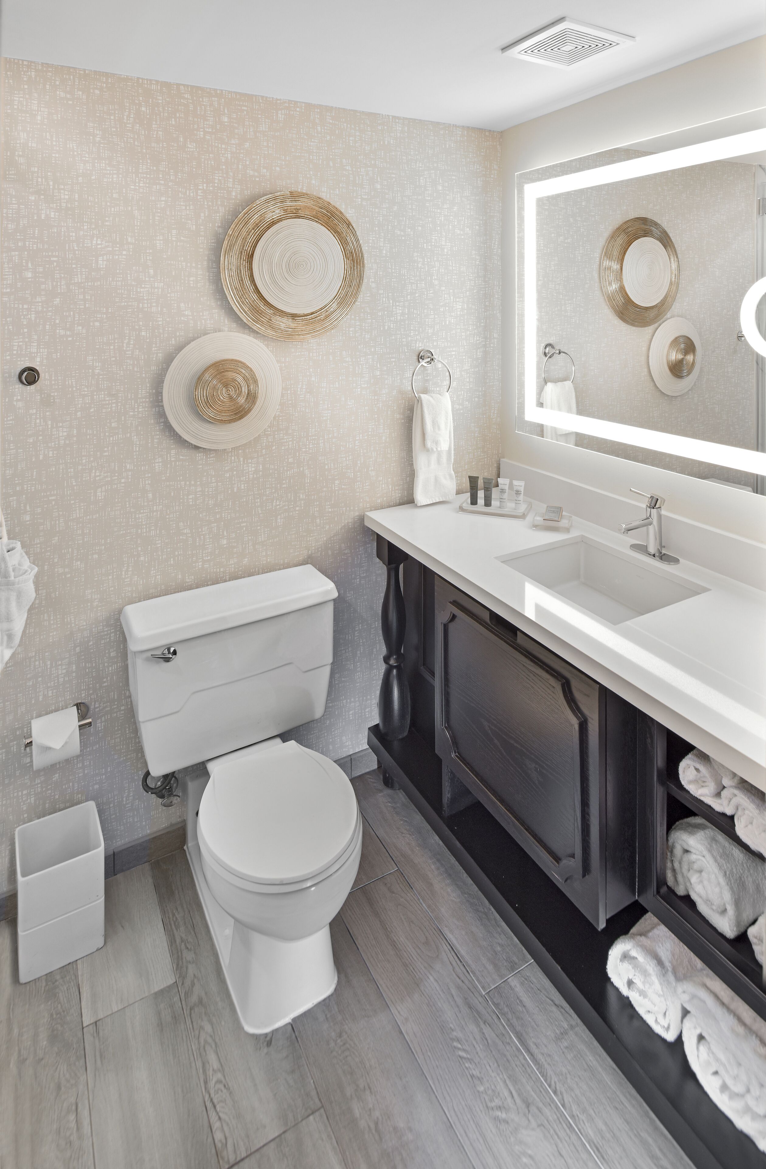 A modern bathroom with a white toilet, a sink, and a mirror.