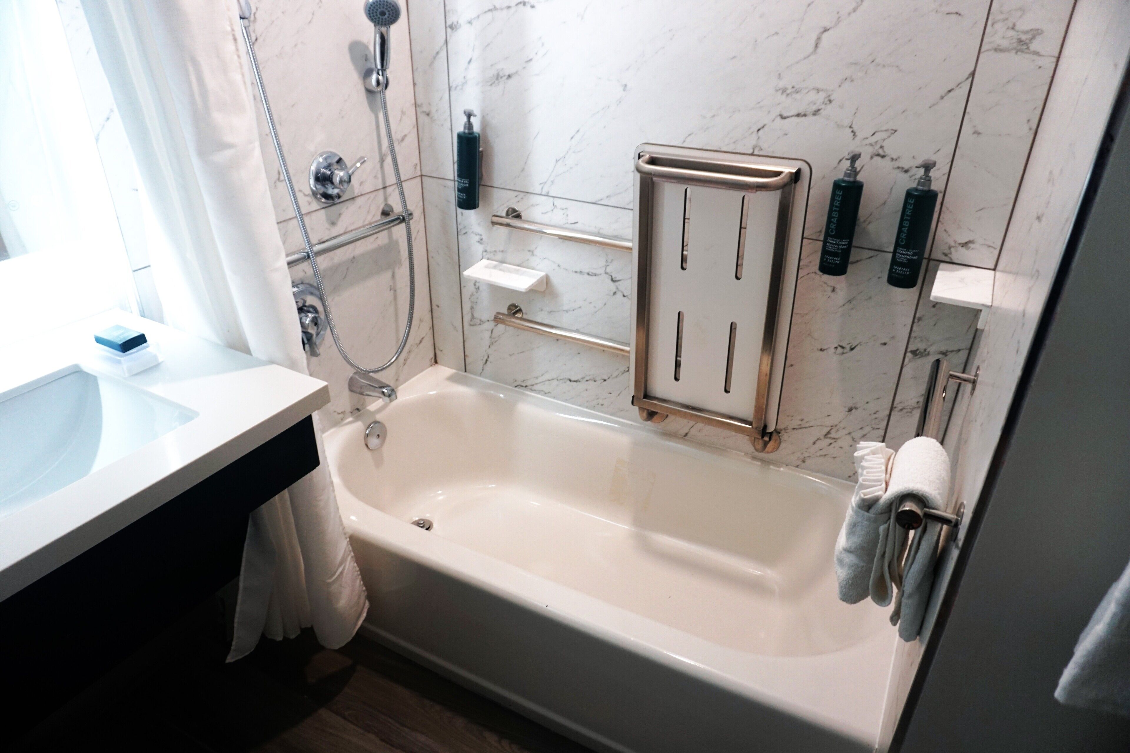 Een moderne badkamer met een bad, een douche en een wastafelmeubel met een wastafel.