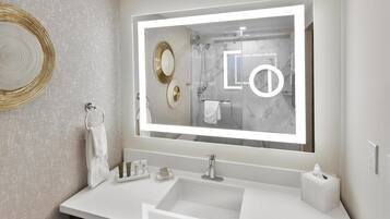 A modern bathroom with a large mirror, a sink, and a towel rack.