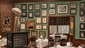 A restaurant with framed photographs on the walls, a trophy, and a menu board listing Super Bowl events.