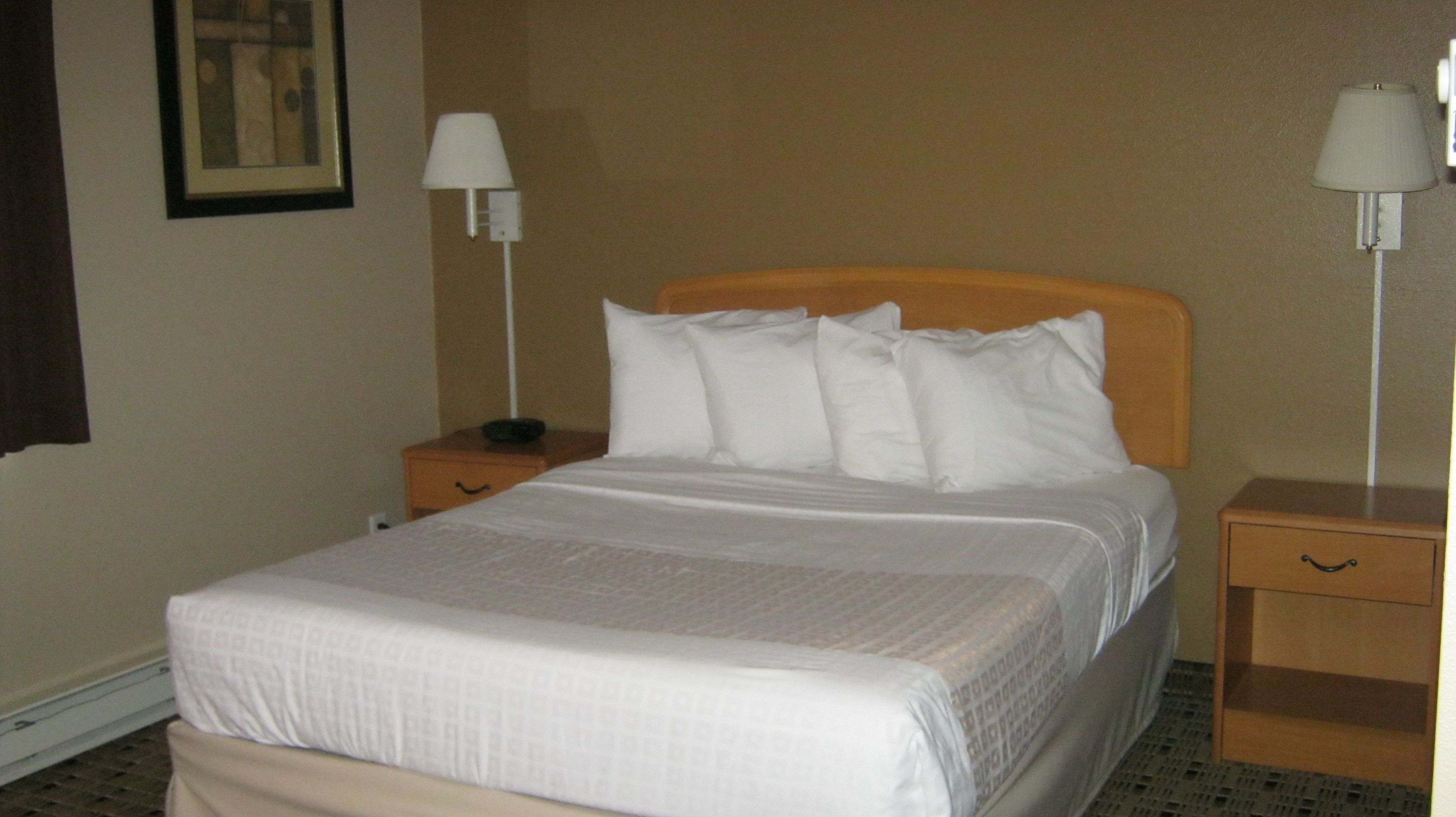 Een hotelkamer met een bed, twee nachtkastjes en twee wandlampen.