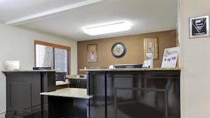 A reception area with a counter, a clock, framed pictures, and a bulletin board. - Americas Best Value Inn & Suites Bismarck (Bismarck)