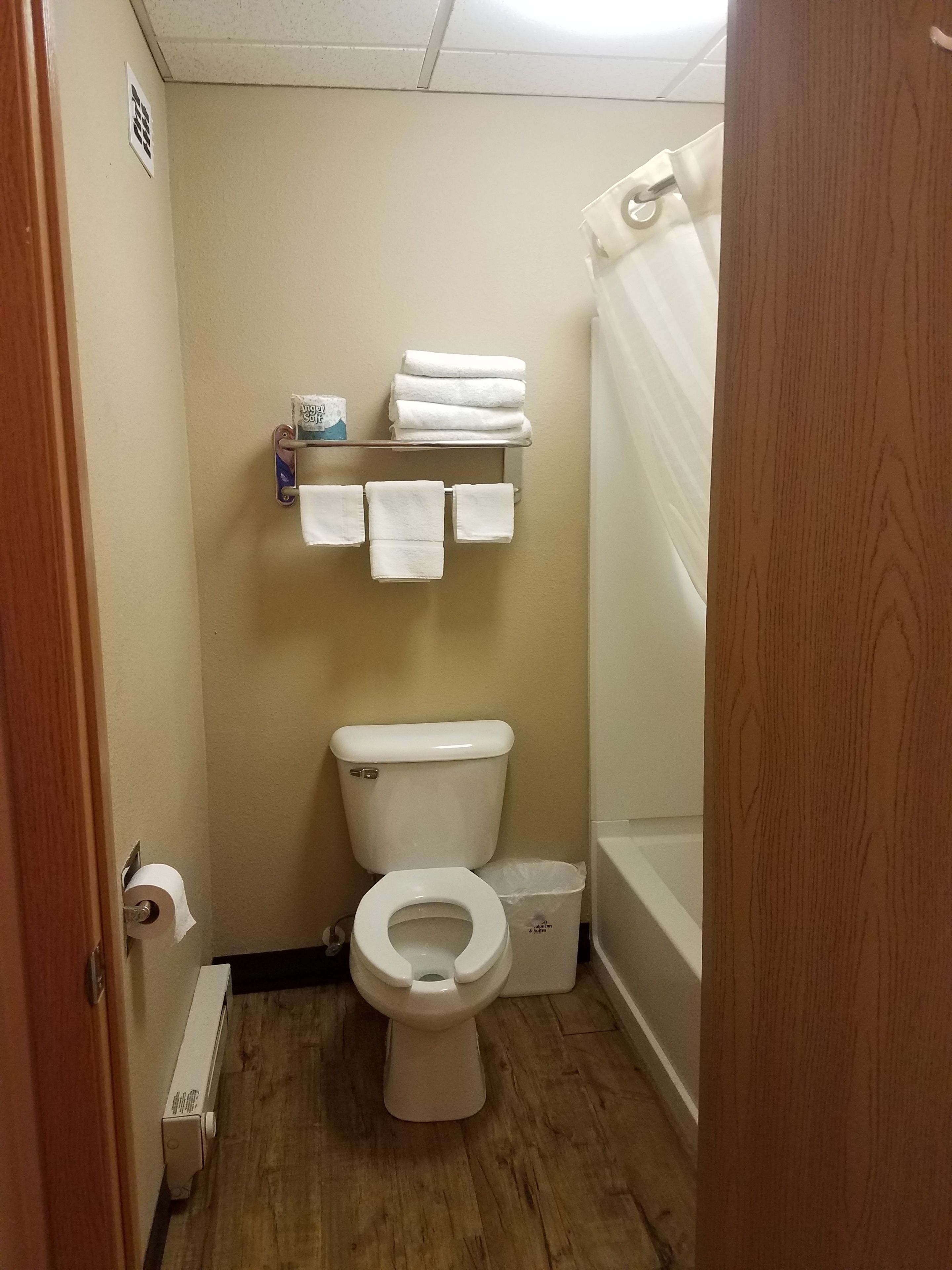 Un baño pequeño con inodoro, un estante con toallas y una cortina de ducha.
