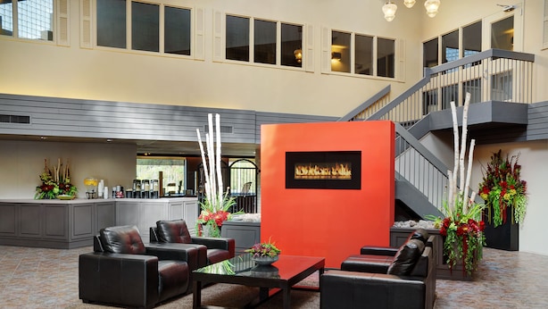 A spacious lobby with a fireplace, leather seating, and a staircase. - Travelway Inn Sudbury (Sudbury)