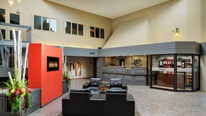 A spacious lobby with a black leather sofa, a red accent wall, and a pantry area. - Travelway Inn Sudbury (Sudbury)
