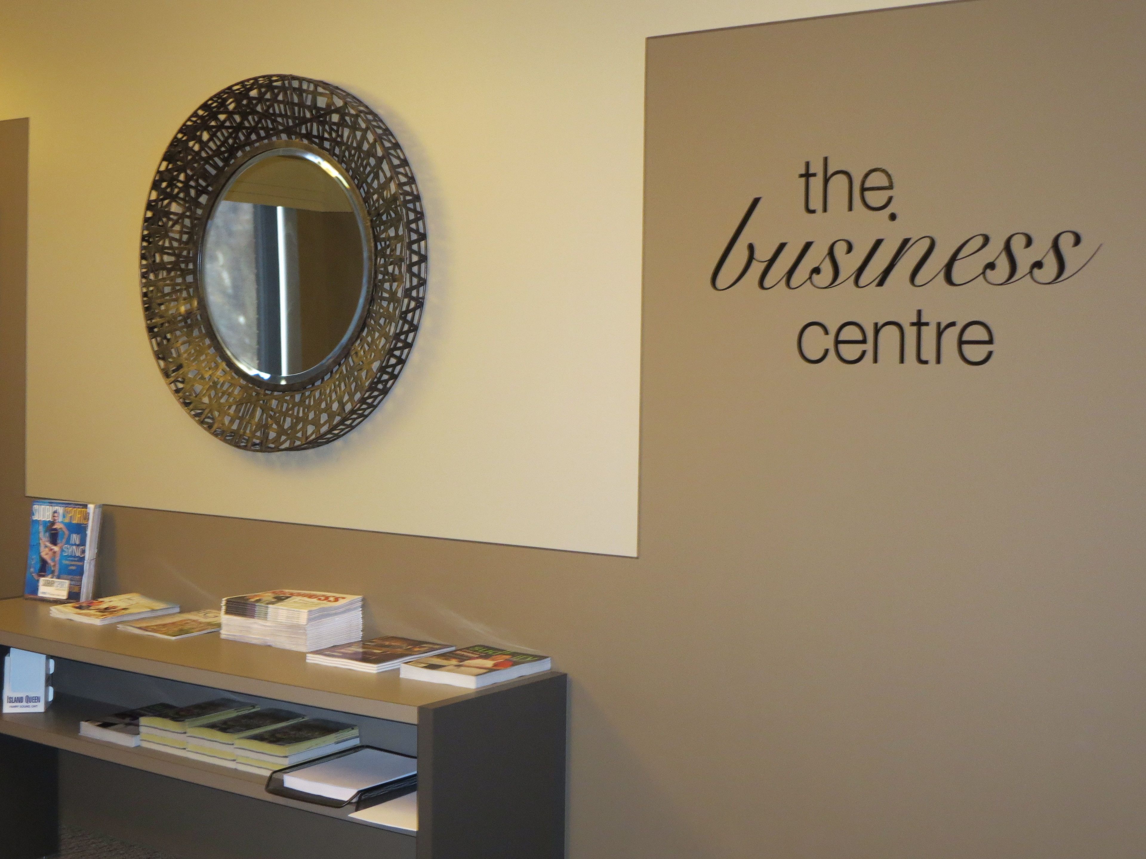 Ein Empfangsschalter mit einem Spiegel darüber und einem Schild an der Wand mit der Aufschrift 'the business centre'.