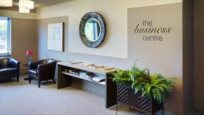 A reception area with a desk, chairs, a mirror, and a sign that reads "the business centre". - Travelway Inn Sudbury (Sudbury)