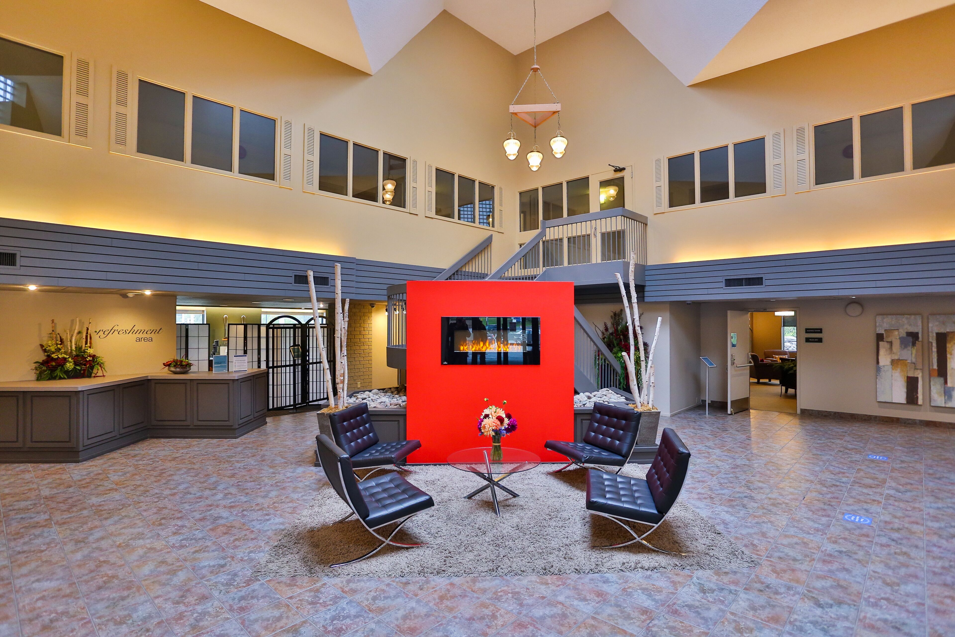 A spacious lobby with a central seating area, a staircase, and a reception desk.
