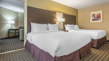 A hotel room with two beds, a nightstand, a lamp, and a painting on the wall.
