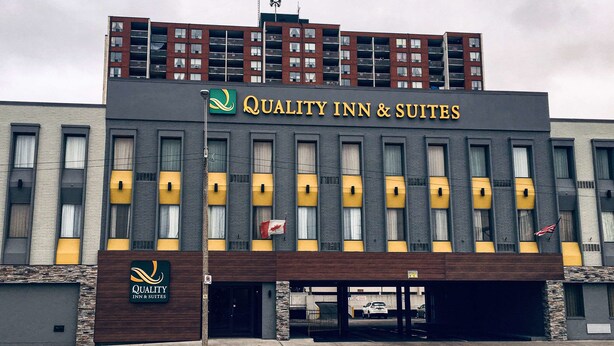 Un hotel llamado "Quality Inn & Suites" con un diseño moderno, que presenta un letrero llamativo y una bandera.