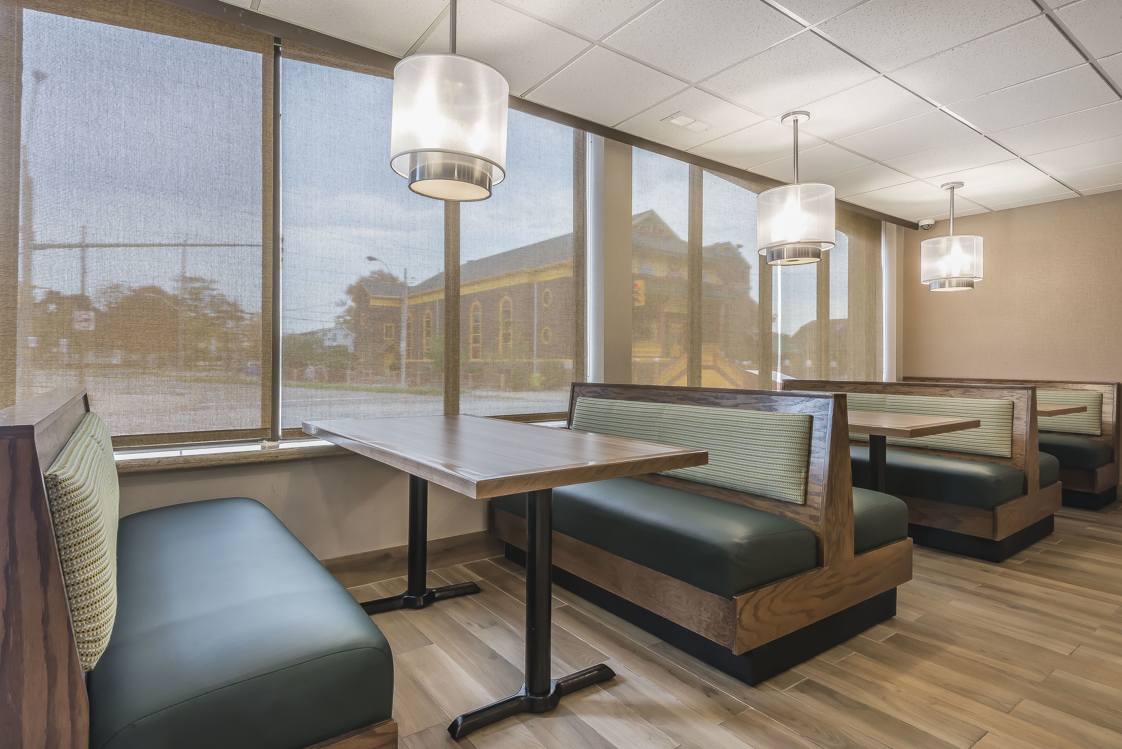 A restaurant interior with booth seating, large windows, and hanging pendant lights.
