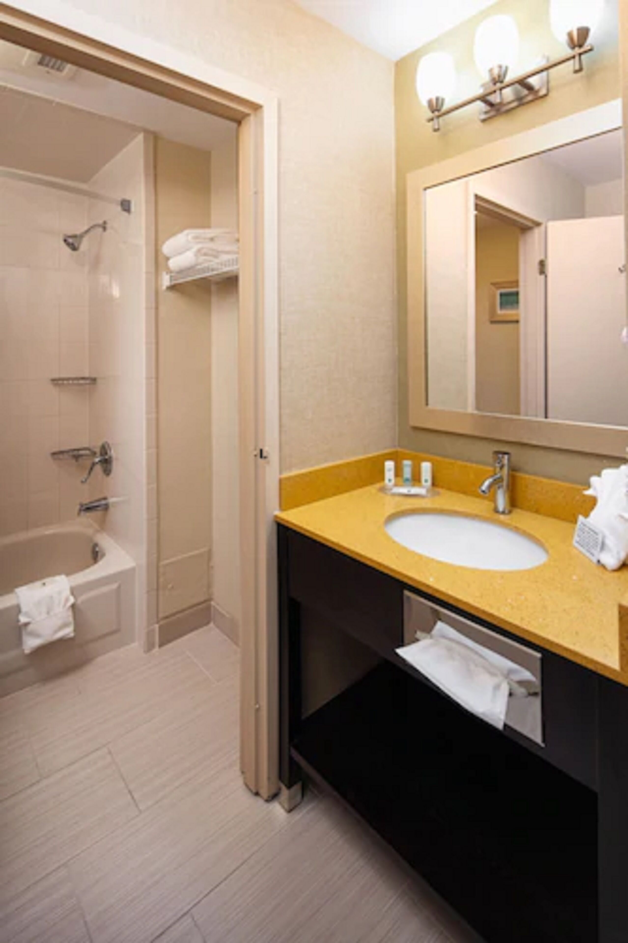 A bathroom with a bathtub, a sink, a mirror, and a towel rack.