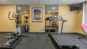 Une salle de sport équipée d’appareils de cardio, notamment des tapis de course et un appareil elliptique.