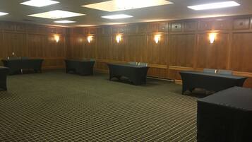 A conference room with wooden paneling, multiple tables, and ceiling lights.