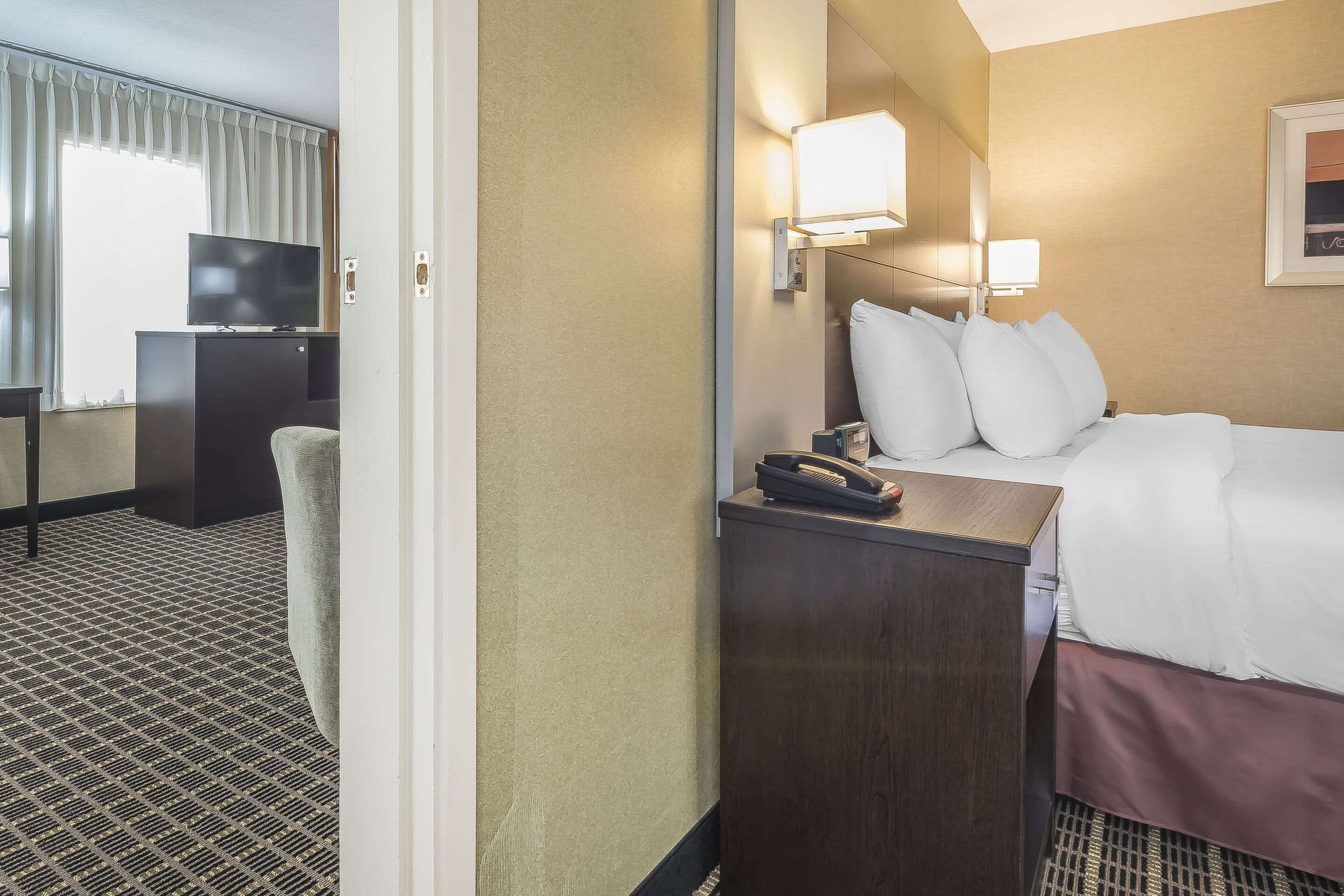 A hotel room with a bed, bedside lamps, a desk with a telephone, and a television on a cabinet.