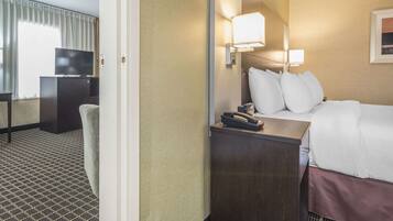 A hotel room with a bed, bedside lamps, a desk with a telephone, and a television on a cabinet.