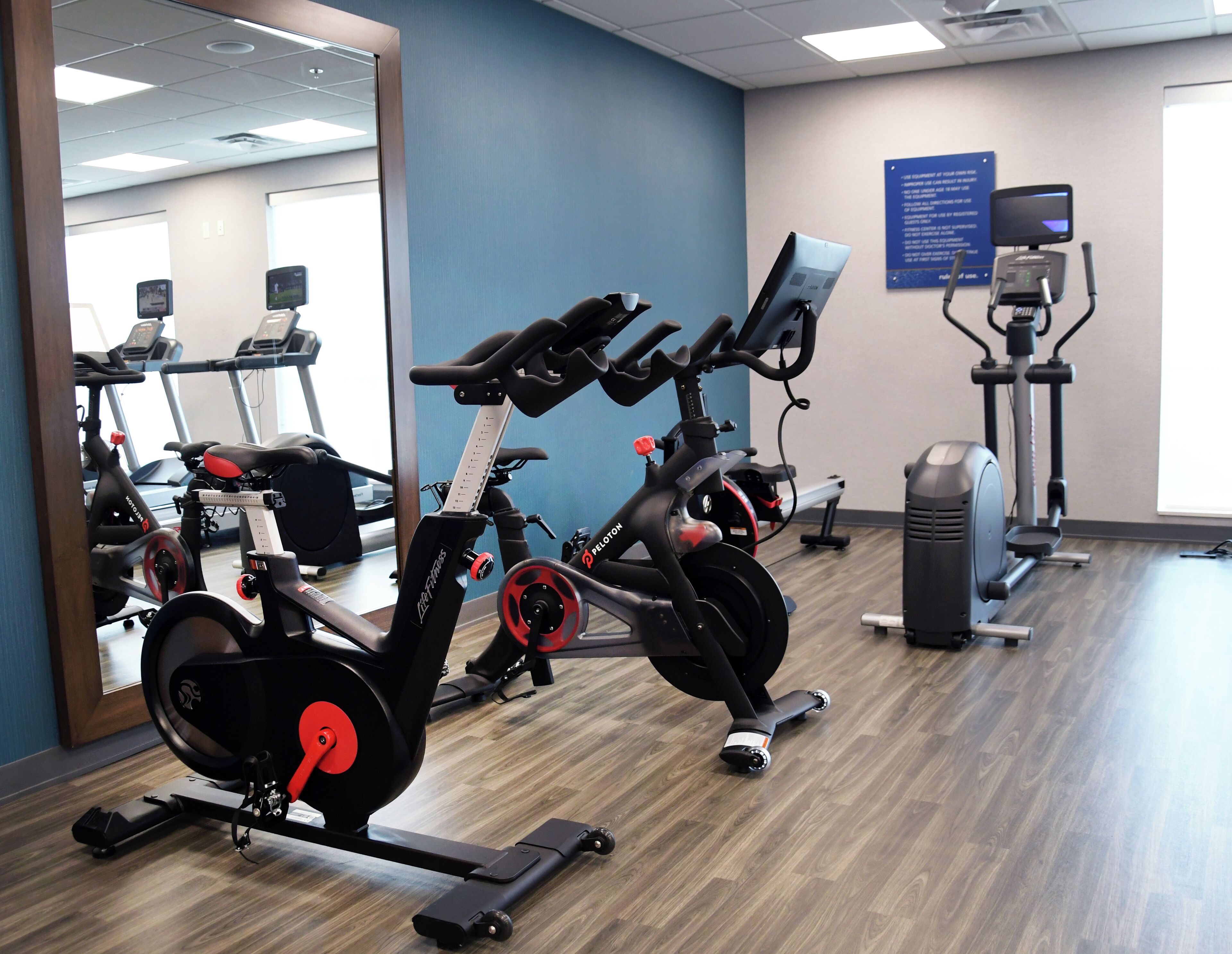 Un gimnasio con bicicletas estáticas, cintas de correr y un espejo.