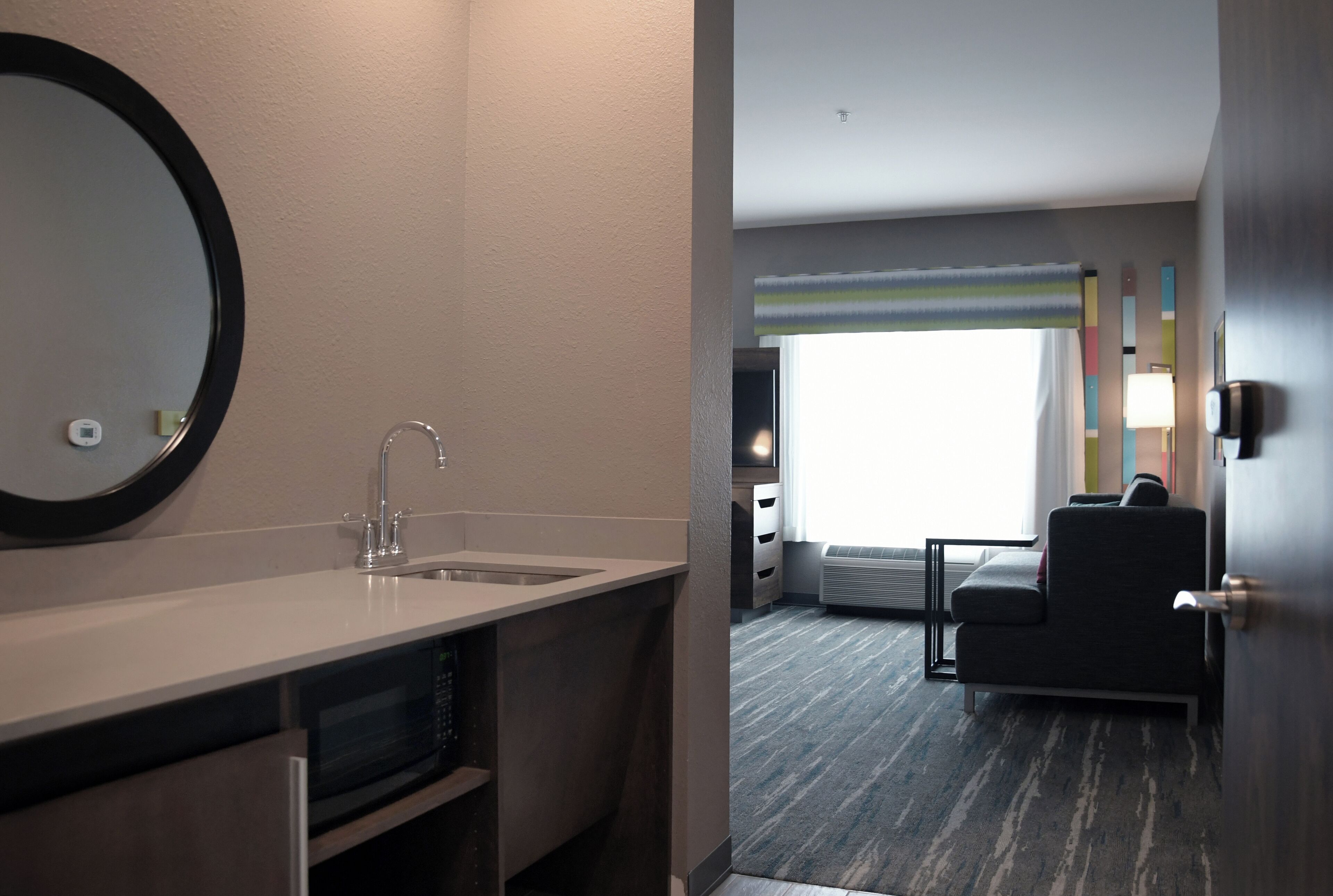 Una habitación de hotel con baño, sofá y ventana.