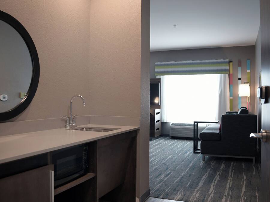 Una habitación de hotel con baño, sofá y ventana.