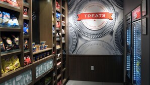 A snack and sundries section with a variety of packaged snacks and a large decorative wall with a 'Treats' sign. - Hampton Inn Glendale Milwaukee, WI (Milwaukee)