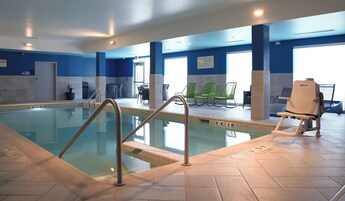 Una piscina con escalera metálica, sillas de descanso y un elevador para sillas de ruedas.