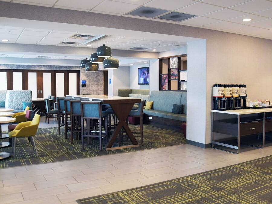 A modern hotel lobby with seating areas, a coffee station, and a reception desk.