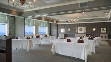 Un salón de conferencias con varias mesas, sillas y un atril.