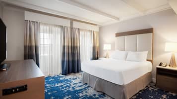 A hotel room with a large bed, a desk, and a TV.