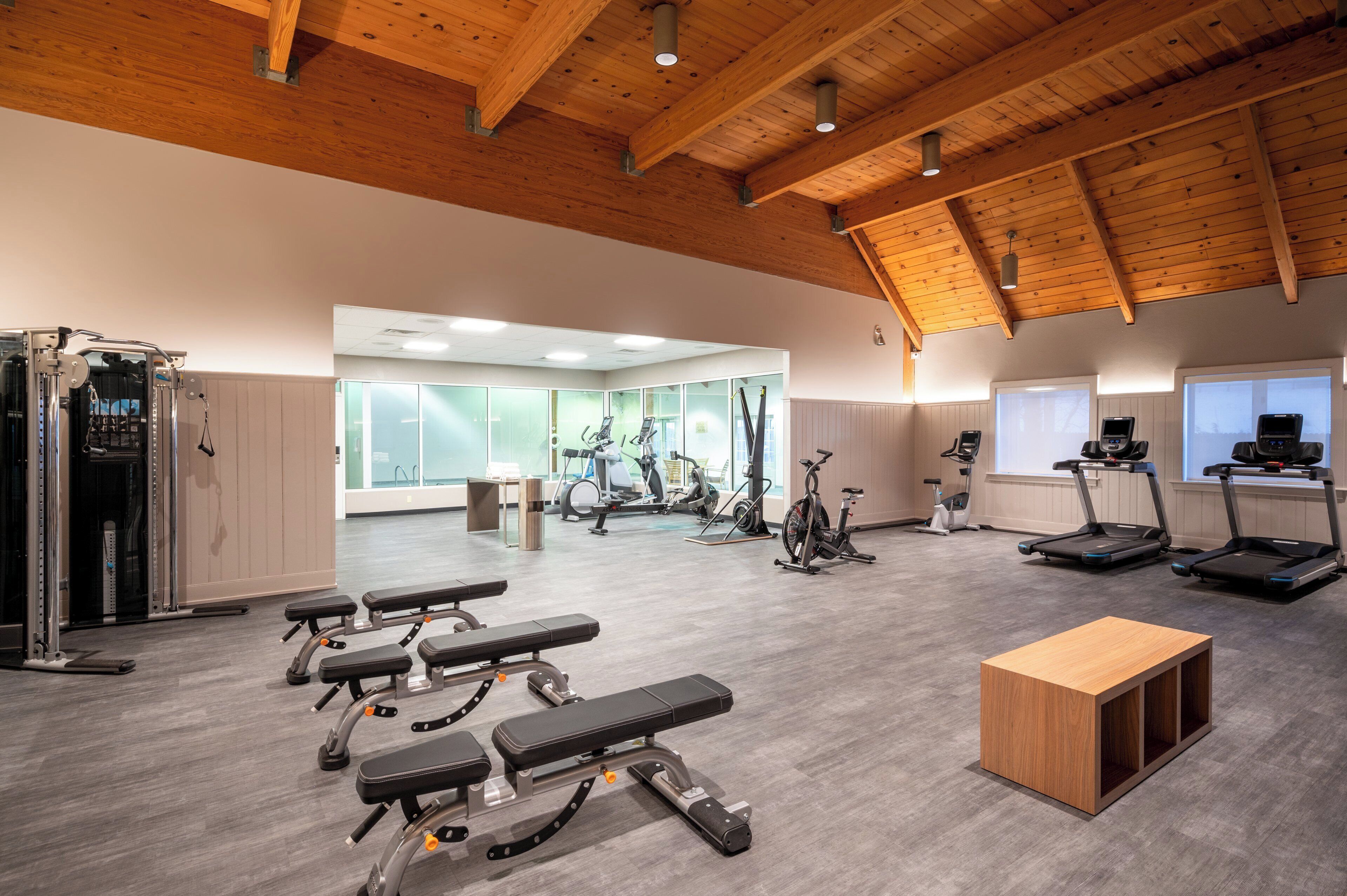 Ett gym med olika typer av träningsutrustning, inklusive löpband, motionscyklar och styrketräningsmaskiner.