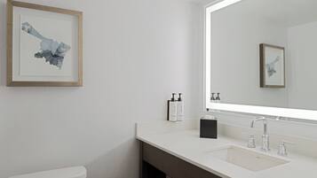 Een moderne badkamer met een wit toilet, een grote spiegel en een witte wastafel met een donkere onderkast.