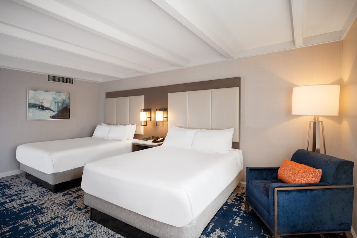 Een hotelkamer met twee bedden, een bureau, een stoel en een lamp.