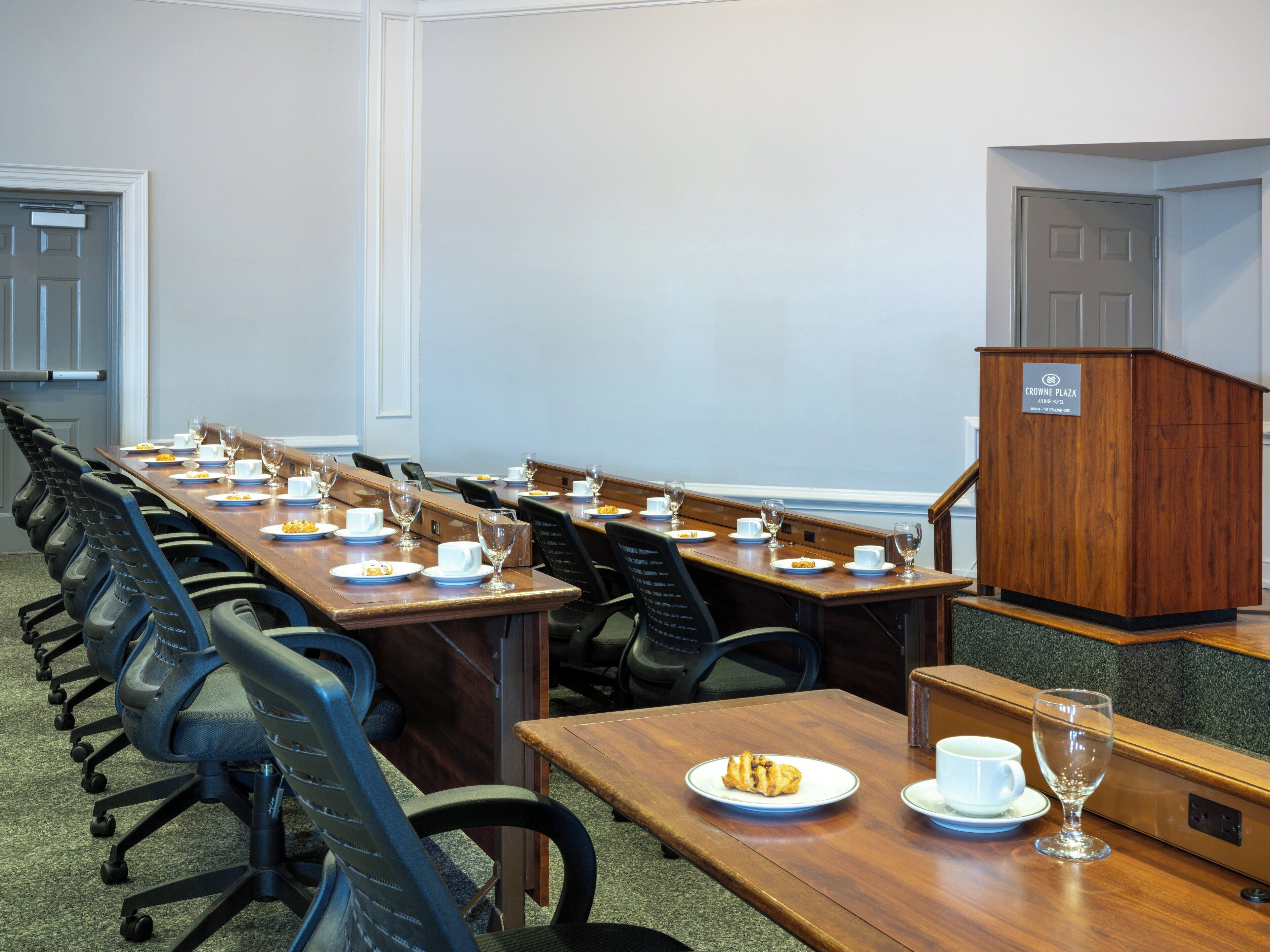 A conference room with a long table, chairs, and a podium.
