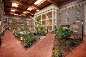 Un amplio patio interior con una zona de estar central, rodeado de exuberante vegetación y un sendero de ladrillo.