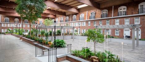 A spacious indoor courtyard with a brick building, columns, and a variety of plants.