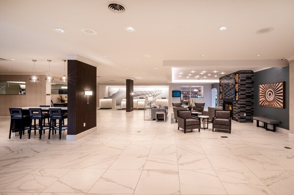 A spacious lobby with a seating area, a reception desk, and a modern fireplace.
