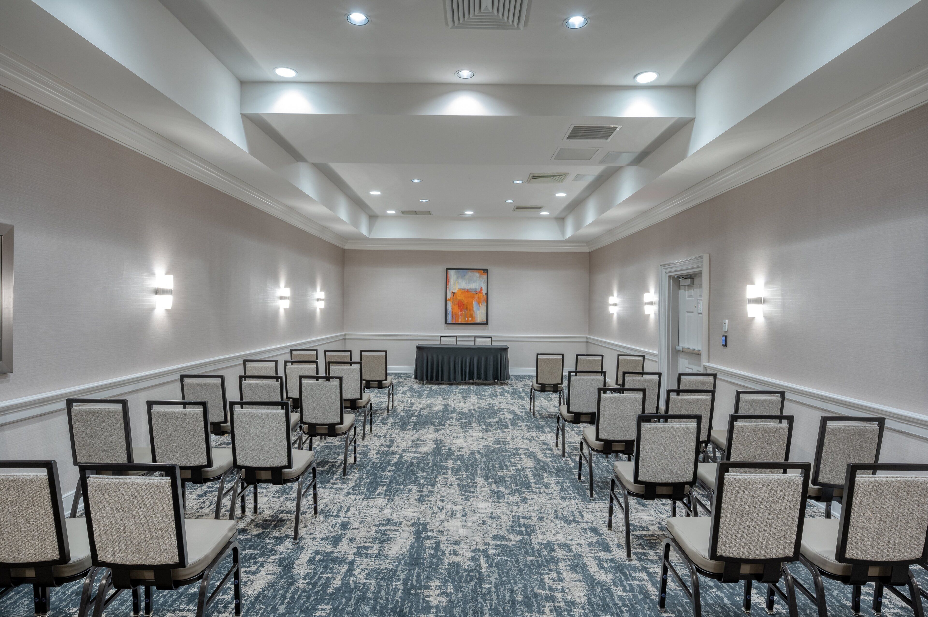 A conference room with rows of chairs, a podium, and a carpeted floor.
