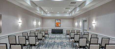 A conference room with rows of chairs, a podium, and a carpeted floor.