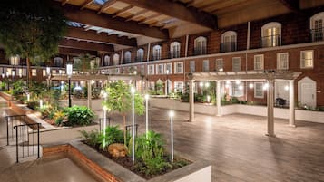 A spacious courtyard with wooden flooring, multiple levels of balconies, and outdoor lighting.