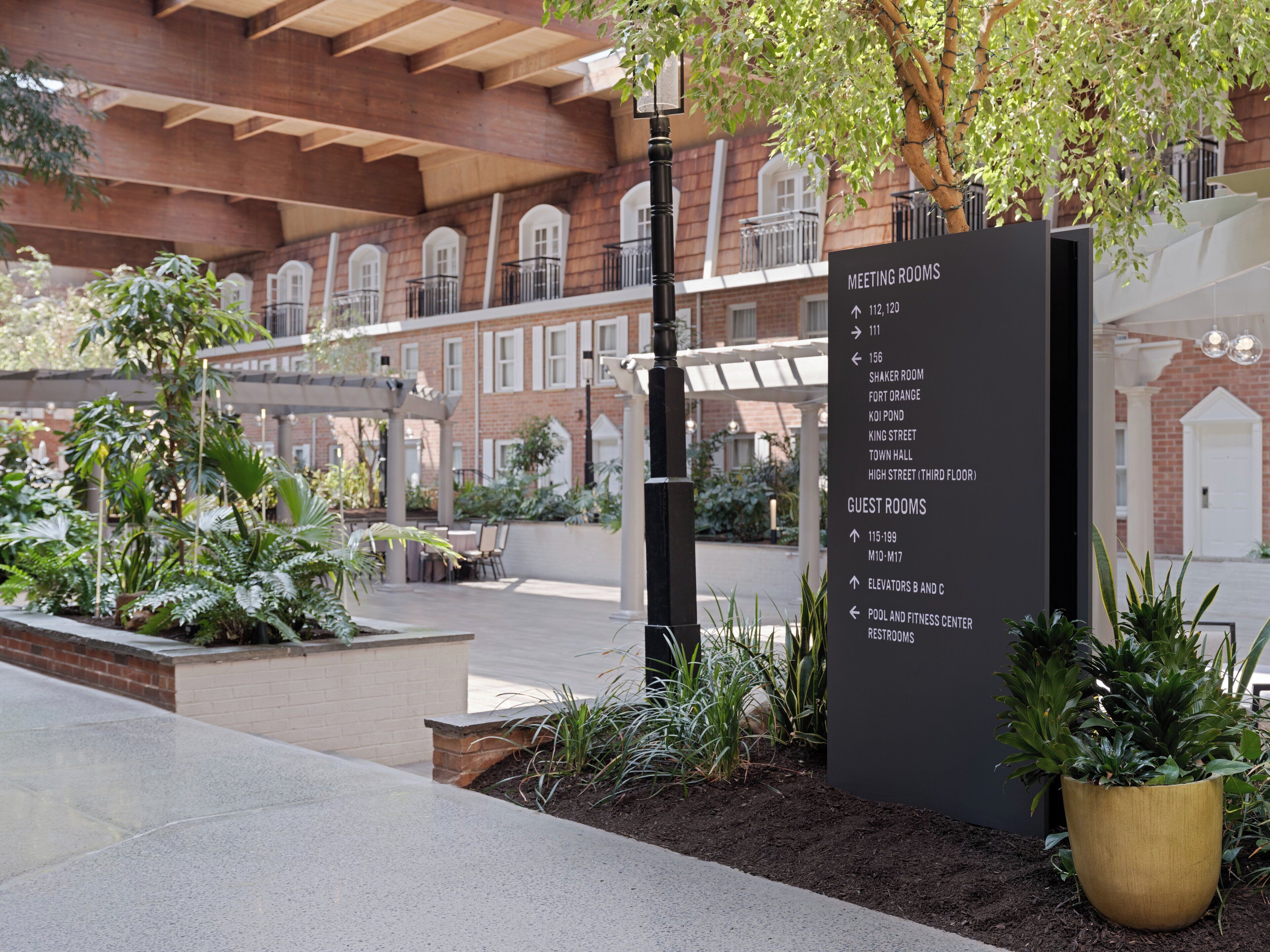 A hotel with a sign listing meeting rooms, guest rooms, and amenities like elevators and a fitness center.