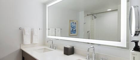 A modern bathroom with two sinks, a large mirror, and a towel rack.