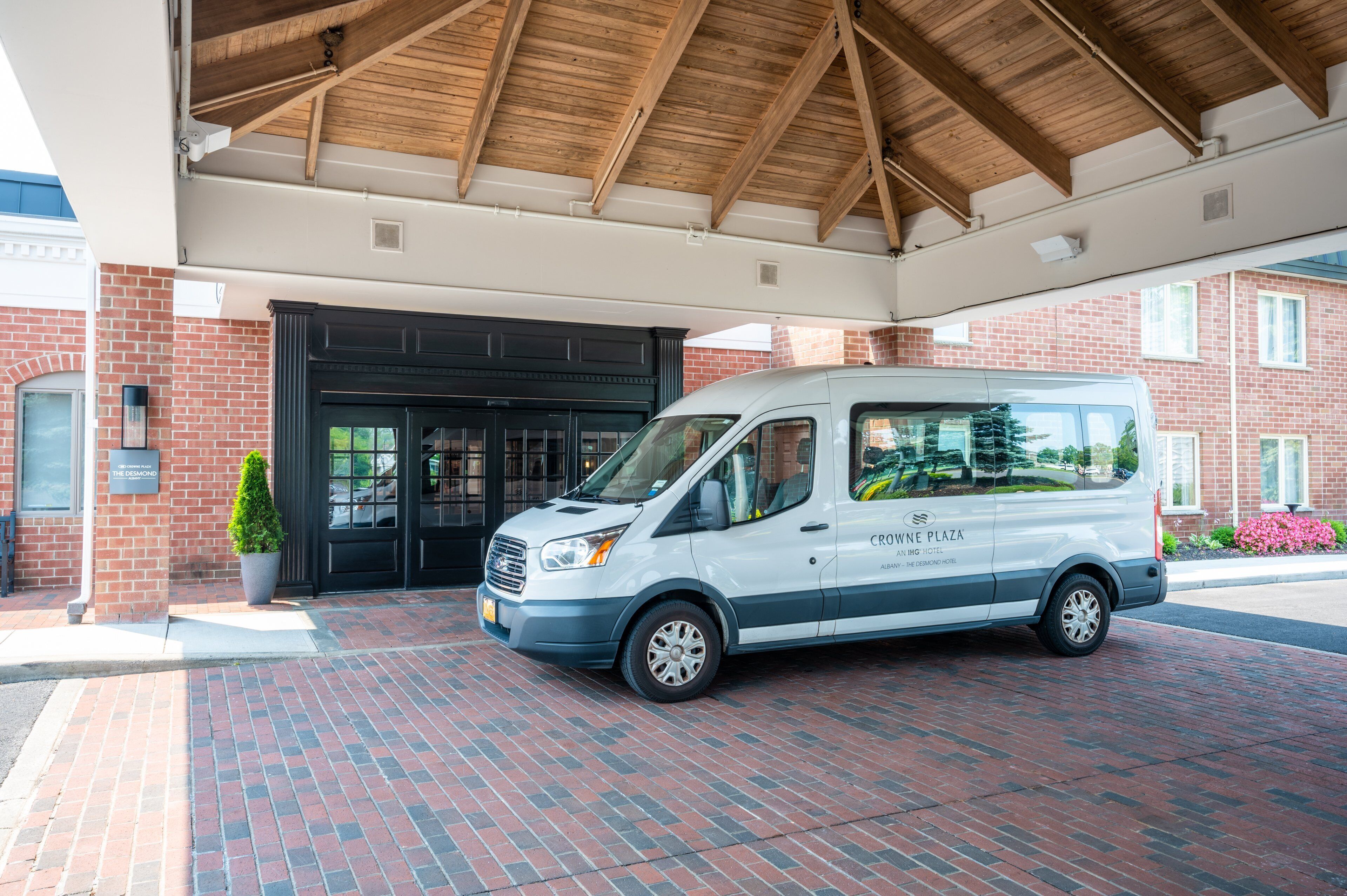 A white van parked in front of a building with a brick facade and a black entrance door.