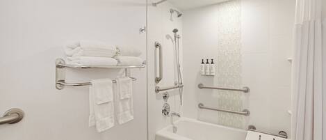 A modern bathroom with a bathtub, shower, handrails, and towel racks.