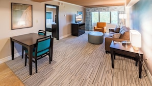 A hotel room with a dining area, a sofa, a TV, and a large window with curtains. - The Boulevard Inn & Bistro (Saint Joseph)