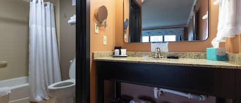 A bathroom with a toilet, shower, and sink.