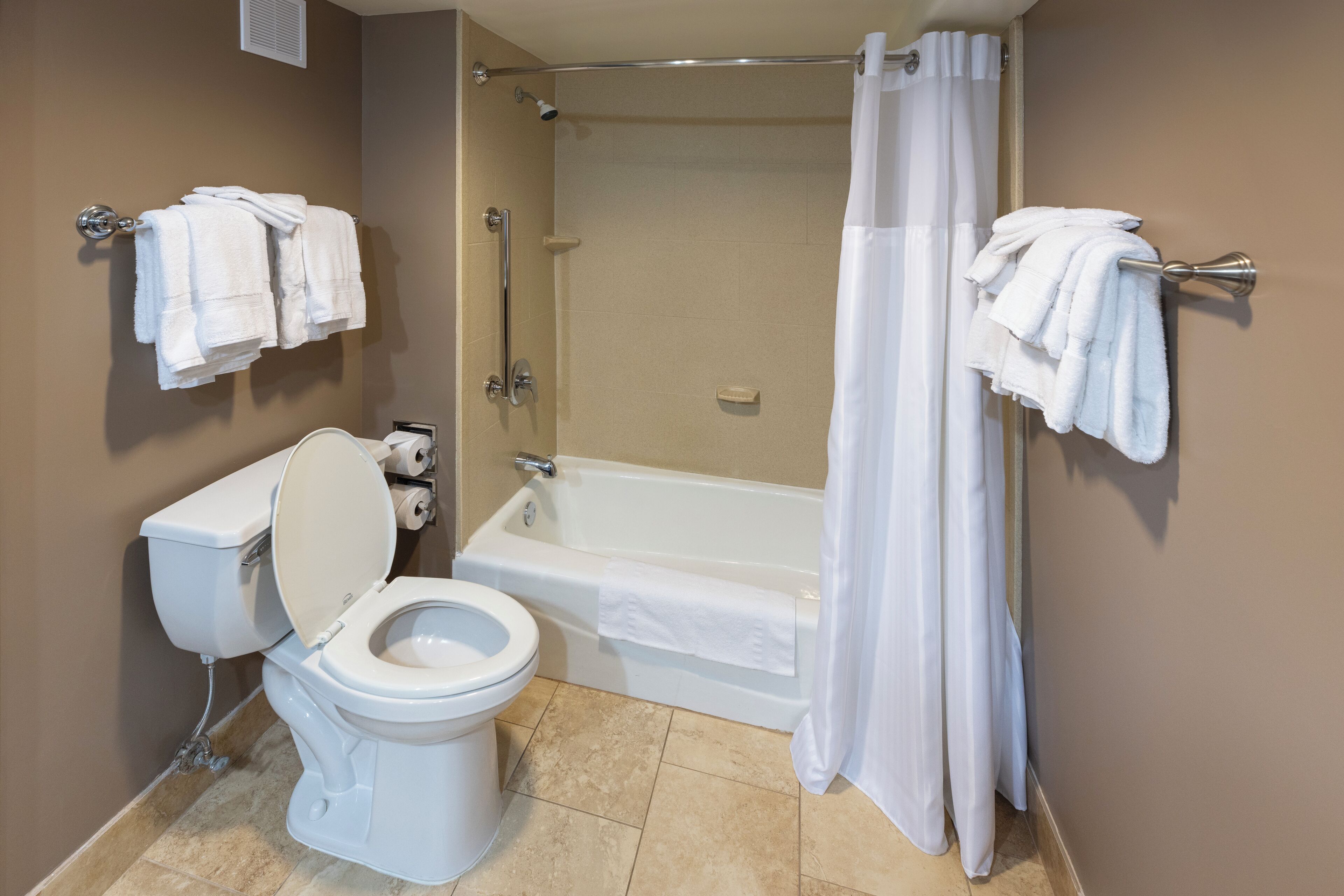 A bathroom with a toilet, bathtub, and shower curtain.