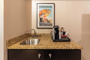 Una cocina con encimera de granito, pileta de acero inoxidable y cafetera.